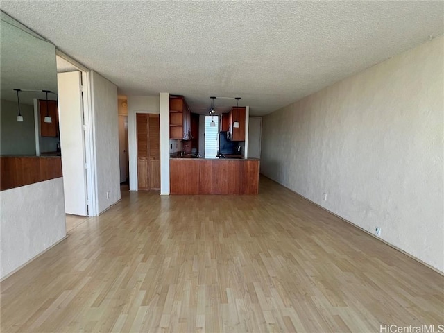 unfurnished living room with a textured ceiling and light hardwood / wood-style floors