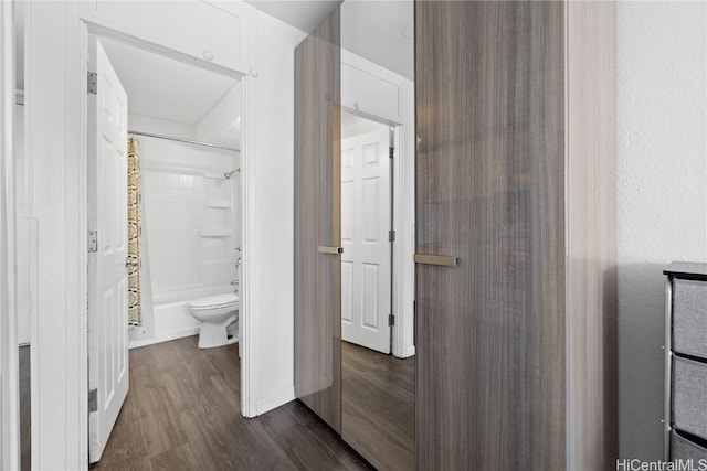 bathroom featuring hardwood / wood-style flooring, shower / bathtub combination with curtain, and toilet