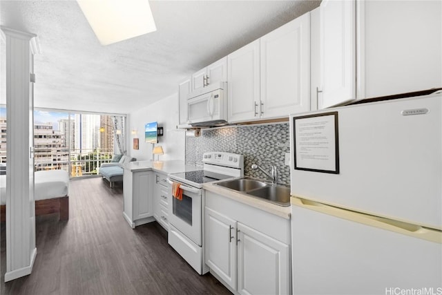 kitchen with sink, white appliances, white cabinetry, tasteful backsplash, and expansive windows