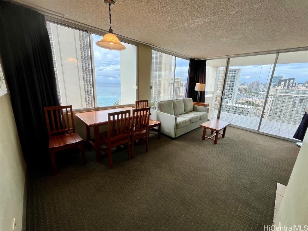 carpeted dining room with a water view, a textured ceiling, and a wall of windows