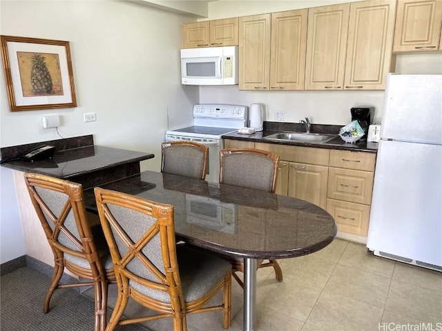 kitchen with sink, light tile patterned floors, light brown cabinetry, and white appliances