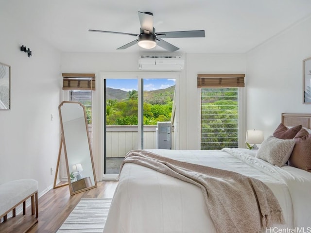 bedroom featuring a wall unit AC, access to outside, ceiling fan, and light hardwood / wood-style floors