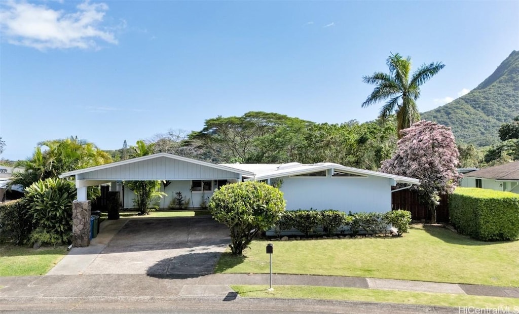 single story home featuring a mountain view, a front yard, and a carport