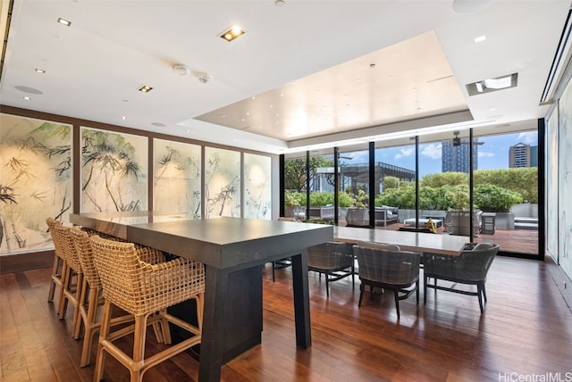 dining space featuring expansive windows, a raised ceiling, and dark wood-type flooring