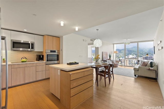 kitchen with a center island, appliances with stainless steel finishes, decorative light fixtures, expansive windows, and backsplash