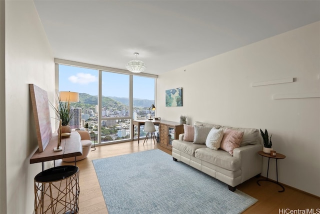 living room with a mountain view, light wood-type flooring, expansive windows, and a notable chandelier