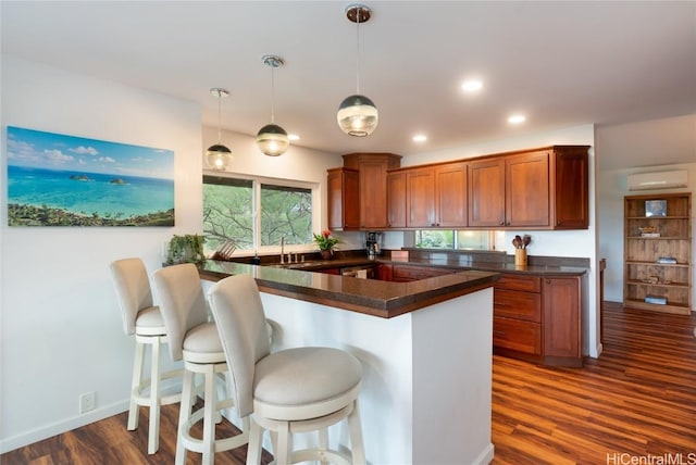 kitchen with kitchen peninsula, pendant lighting, a breakfast bar, and a wall mounted air conditioner