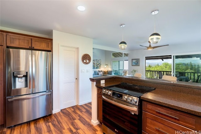 kitchen with stainless steel appliances, dark stone countertops, dark hardwood / wood-style floors, and pendant lighting