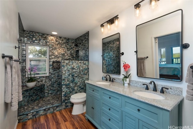 bathroom featuring hardwood / wood-style flooring, toilet, walk in shower, and vanity