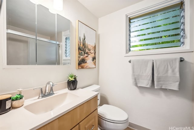 bathroom featuring toilet, vanity, and an enclosed shower