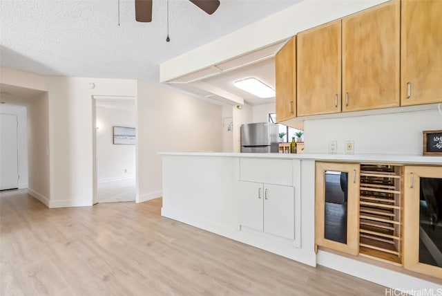 kitchen featuring light hardwood / wood-style floors, a textured ceiling, stainless steel fridge, and ceiling fan