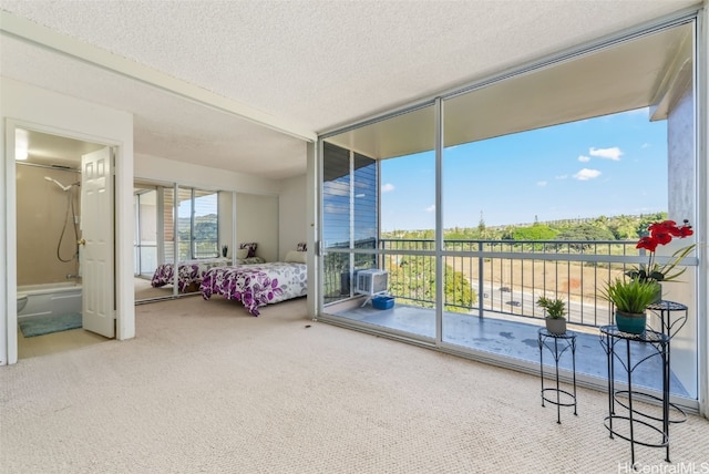 carpeted bedroom with expansive windows, a textured ceiling, ensuite bath, and multiple windows