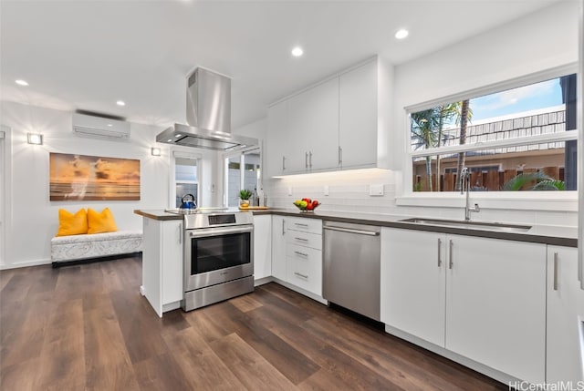 kitchen with white cabinetry, sink, island exhaust hood, stainless steel appliances, and a wall unit AC