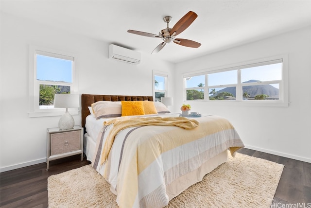 bedroom with a mountain view, dark hardwood / wood-style floors, a wall mounted air conditioner, and ceiling fan