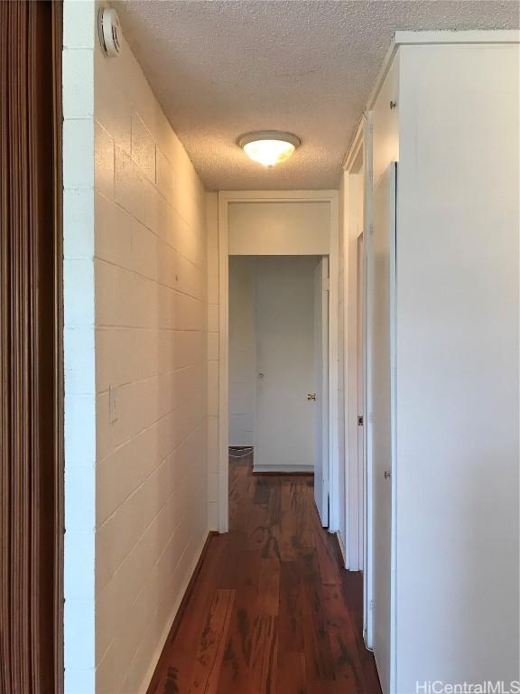 hall with dark wood-type flooring and a textured ceiling