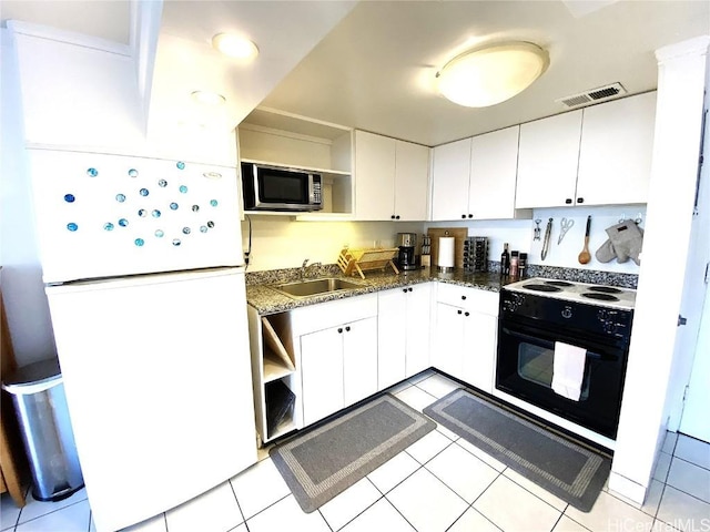 kitchen featuring sink, light tile patterned floors, white cabinetry, black electric range, and white fridge