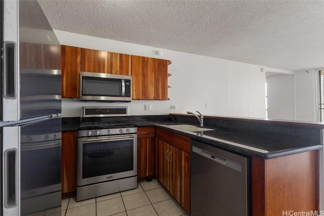 kitchen with light tile patterned flooring, appliances with stainless steel finishes, kitchen peninsula, and sink