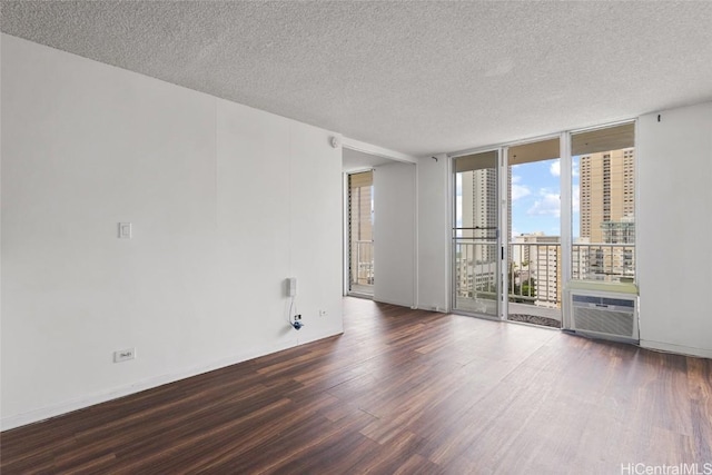 empty room with dark wood-type flooring, expansive windows, and a textured ceiling