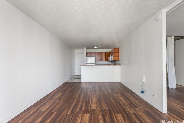 unfurnished living room featuring dark wood-type flooring and a textured ceiling