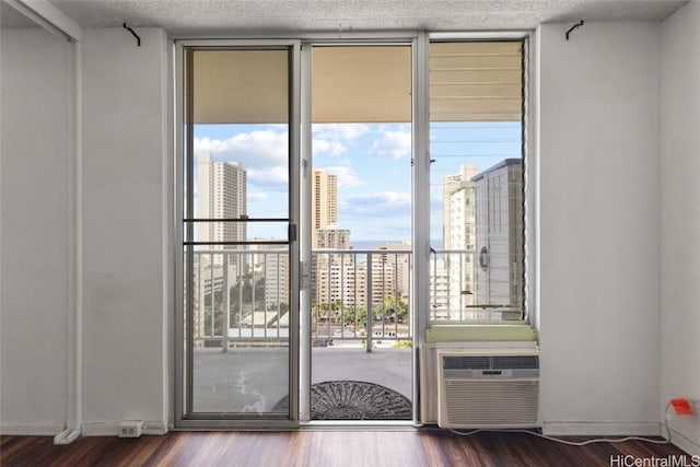 doorway to outside with a wall mounted air conditioner, hardwood / wood-style floors, a textured ceiling, and a wall of windows