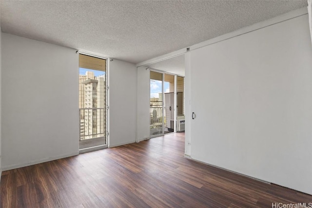 empty room with a wall of windows, dark hardwood / wood-style floors, and a textured ceiling