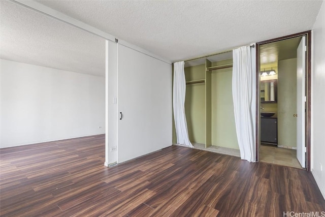 unfurnished bedroom with a textured ceiling, dark hardwood / wood-style flooring, and a closet