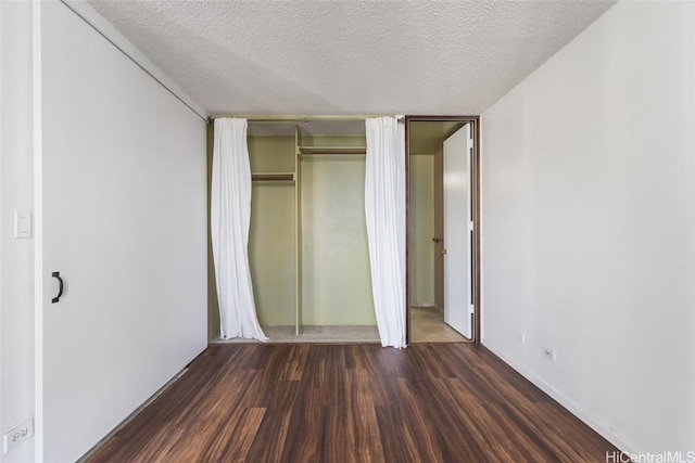 unfurnished bedroom with dark wood-type flooring, a textured ceiling, and a closet