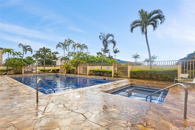 pool featuring a hot tub, a patio, and fence