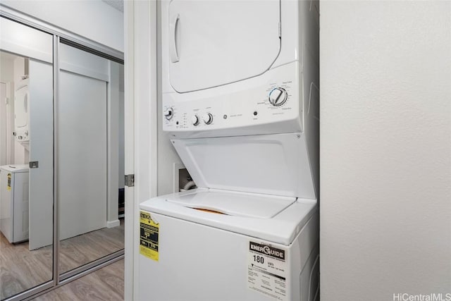 laundry room featuring stacked washing maching and dryer and light hardwood / wood-style floors