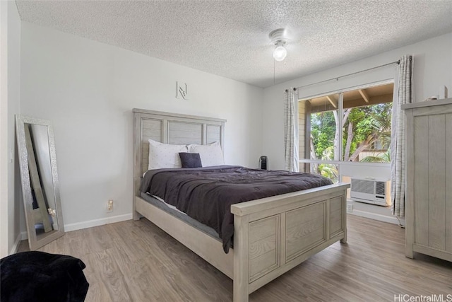 bedroom featuring ceiling fan, a textured ceiling, light hardwood / wood-style flooring, and cooling unit