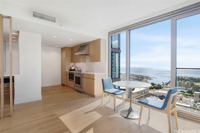 dining area featuring a water view, light hardwood / wood-style floors, and floor to ceiling windows