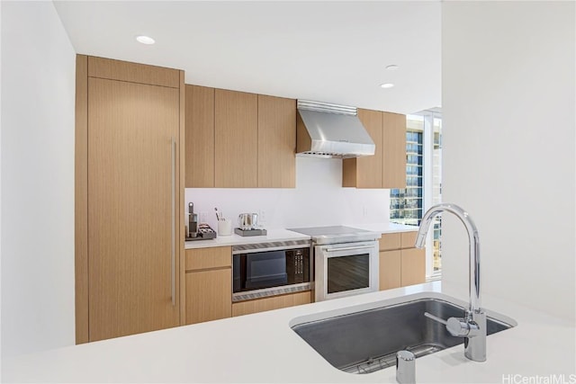 kitchen with wall chimney exhaust hood, sink, built in microwave, and oven