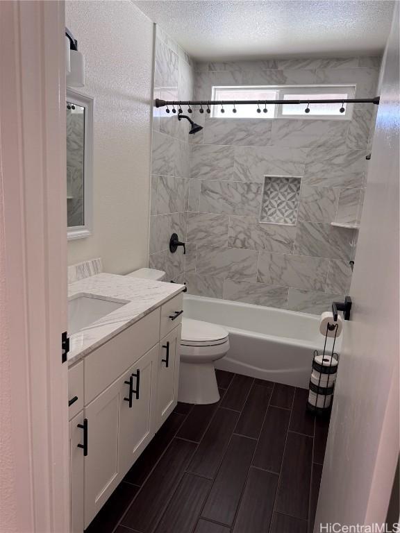 full bathroom with toilet, vanity, tiled shower / bath combo, and a textured ceiling