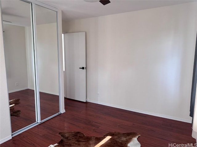 unfurnished bedroom featuring ceiling fan, dark wood-type flooring, and a closet