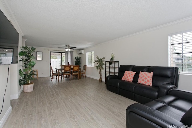 living room featuring a wall mounted air conditioner, light hardwood / wood-style floors, a textured ceiling, and ornamental molding