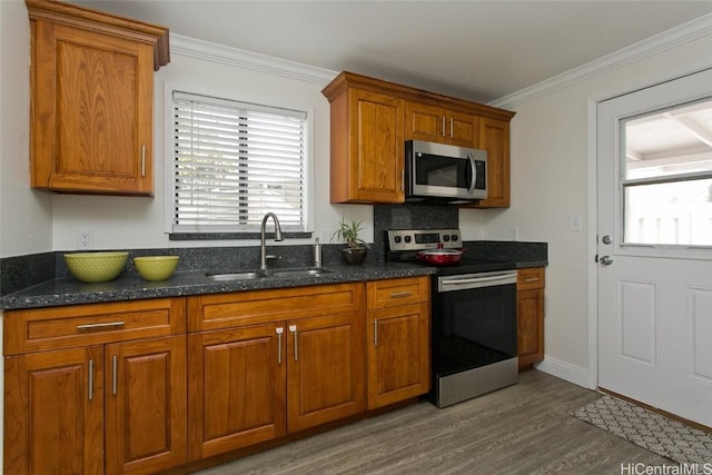 kitchen featuring sink, backsplash, dark wood-type flooring, dark stone counters, and stainless steel appliances