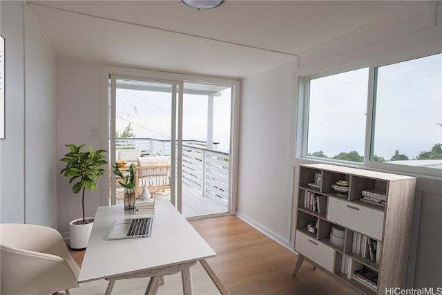 home office with light hardwood / wood-style flooring and a healthy amount of sunlight