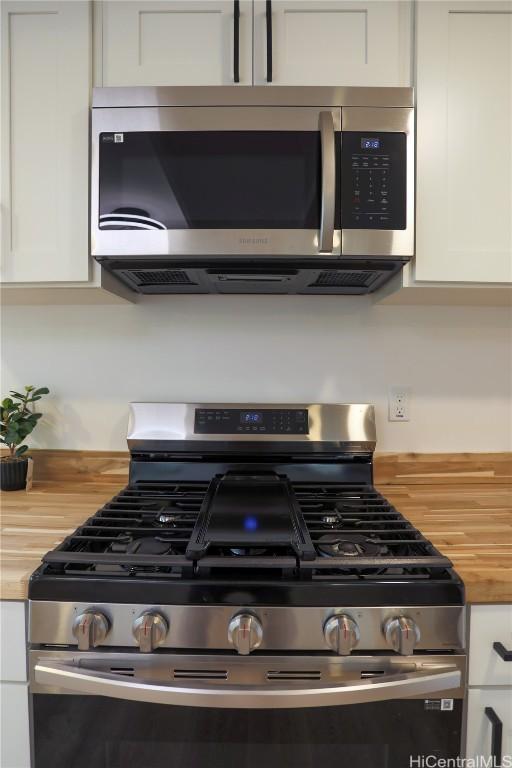 room details featuring stainless steel appliances, white cabinetry, and butcher block counters