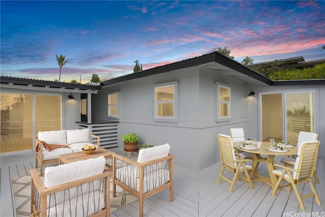 back house at dusk with a wooden deck and outdoor lounge area