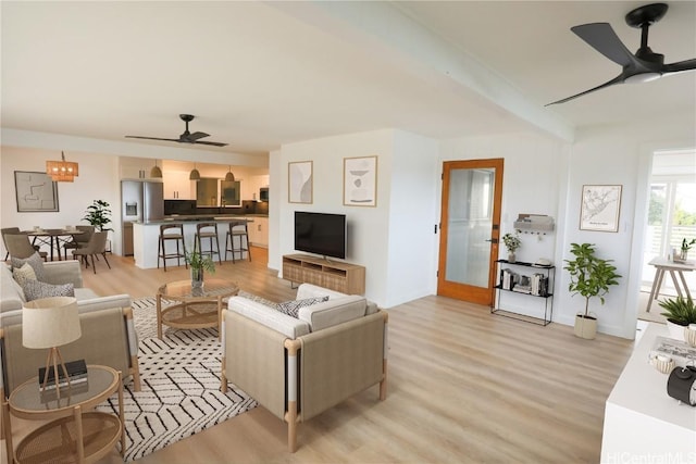 living room with beam ceiling, light hardwood / wood-style flooring, and ceiling fan