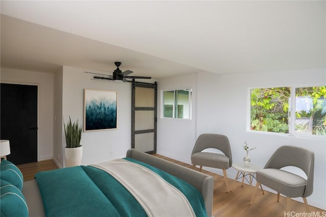 bedroom featuring hardwood / wood-style floors, a barn door, and ceiling fan