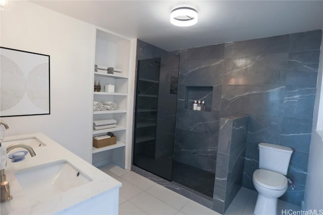 bathroom featuring built in shelves, tile patterned floors, toilet, a tile shower, and vanity