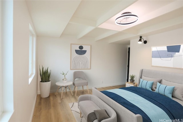 bedroom with beamed ceiling and light wood-type flooring