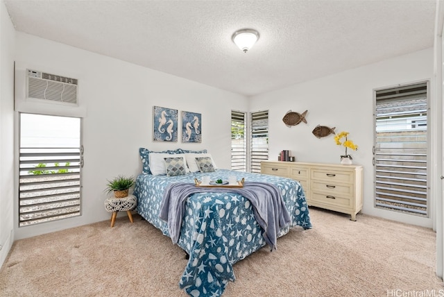 bedroom with an AC wall unit, light carpet, and a textured ceiling