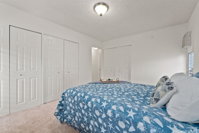 bedroom featuring multiple closets, carpet flooring, and a textured ceiling