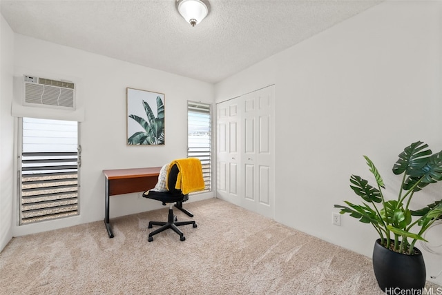 carpeted office space featuring a textured ceiling and a wall unit AC