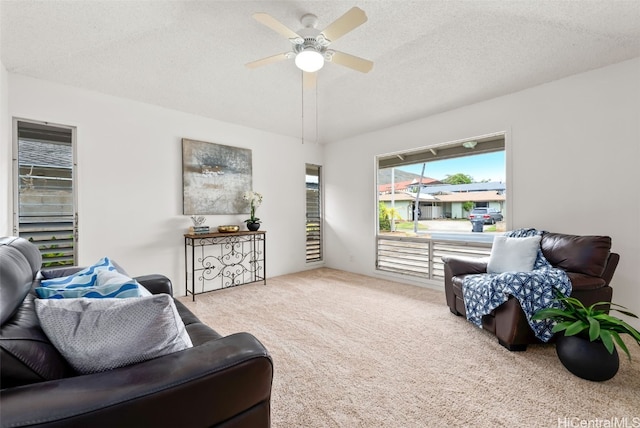 living room with ceiling fan, light carpet, and a textured ceiling