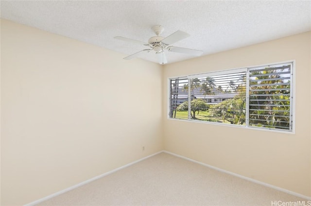 carpeted spare room with ceiling fan, baseboards, and a textured ceiling