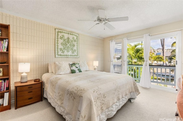 bedroom with a textured ceiling, access to outside, ceiling fan, and light carpet