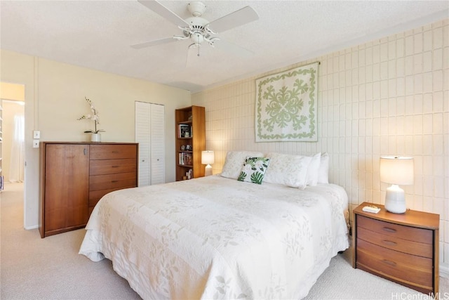 bedroom featuring ceiling fan, light carpet, a closet, and tile walls